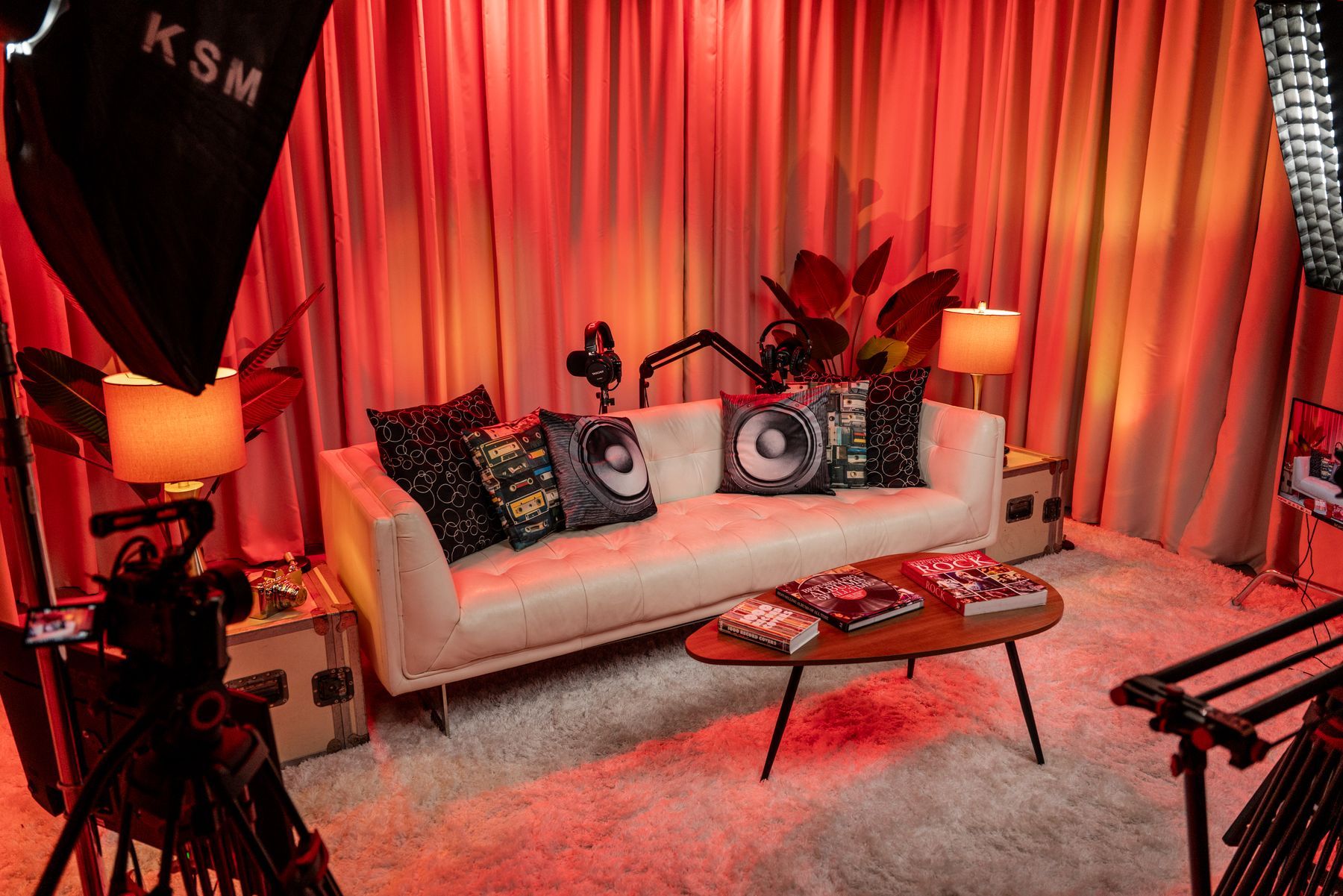 Living room podcast set with white leather sofa, lamps and three-camera setup in a Miami podcast studio