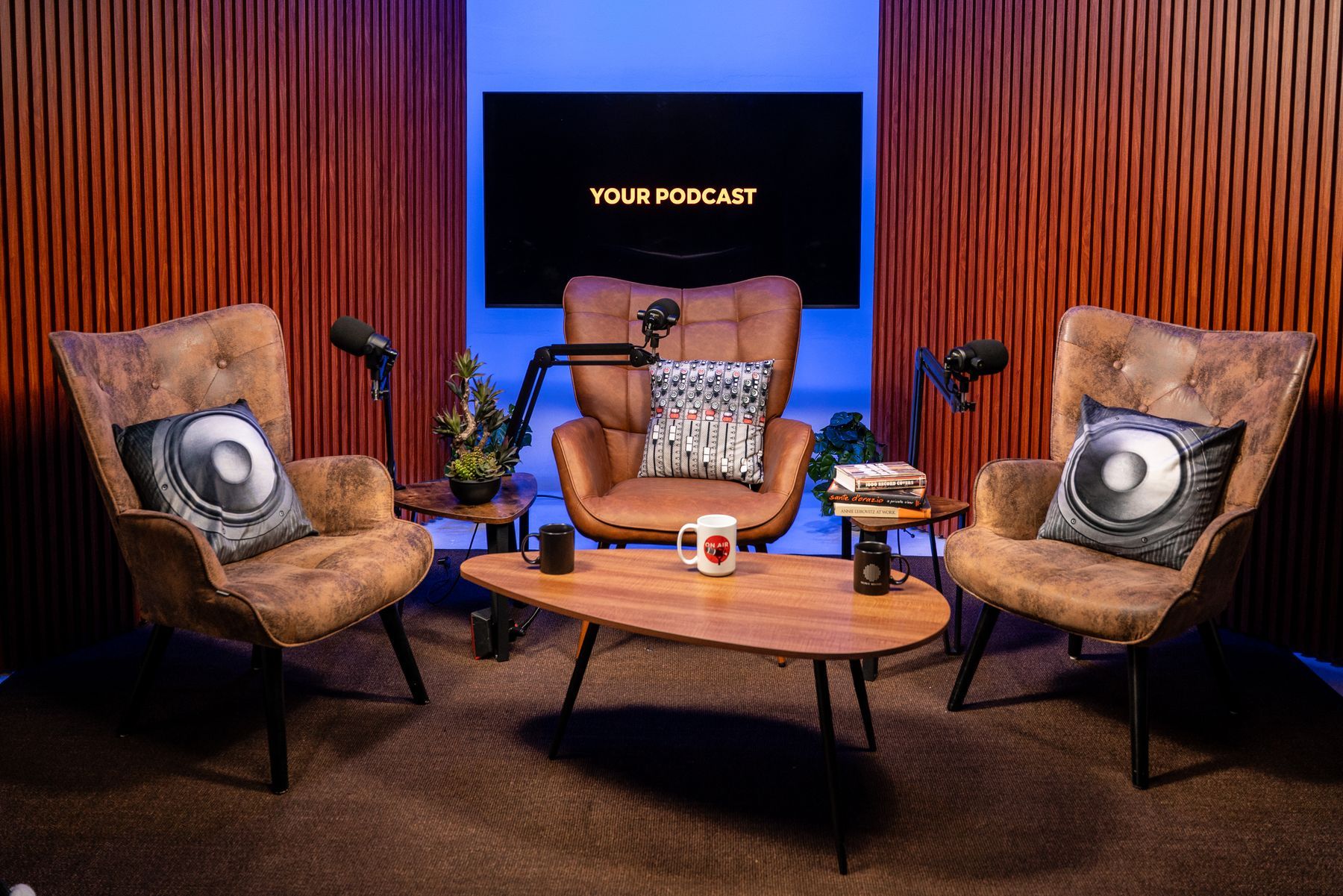 Three-guest podcast set with armchairs, boom-arm microphones and blue lighting, KSM Podcast Studio Miami